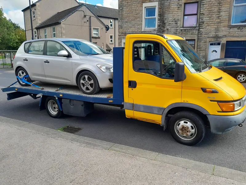Scrap car bought and loaded onto a recovery truck on a Bolton street